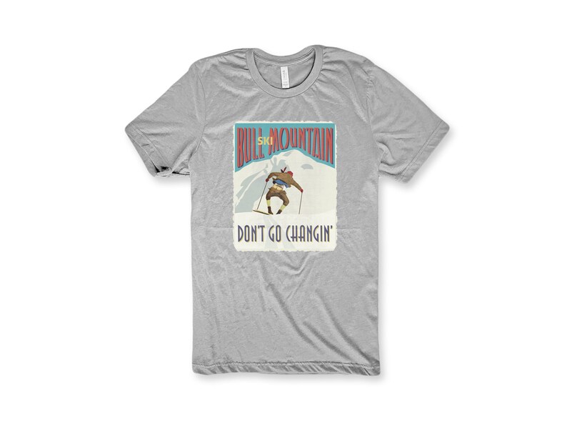 K&ouml;nnte beinhalten: Graues T-Shirt mit einer Grafik im Vintage-Stil eines Skifahrers auf einem Berg. Die Grafik lautet "Bull Mountain Ski" und "Don't Go Changin'."