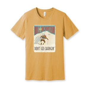 K&ouml;nnte beinhalten: Ein senfgelbes T-Shirt mit einer Grafik im Vintage-Stil eines Skifahrers auf einem Berg. Die Grafik lautet "Bull Mountain Ski" und "Don't Go Changin'".