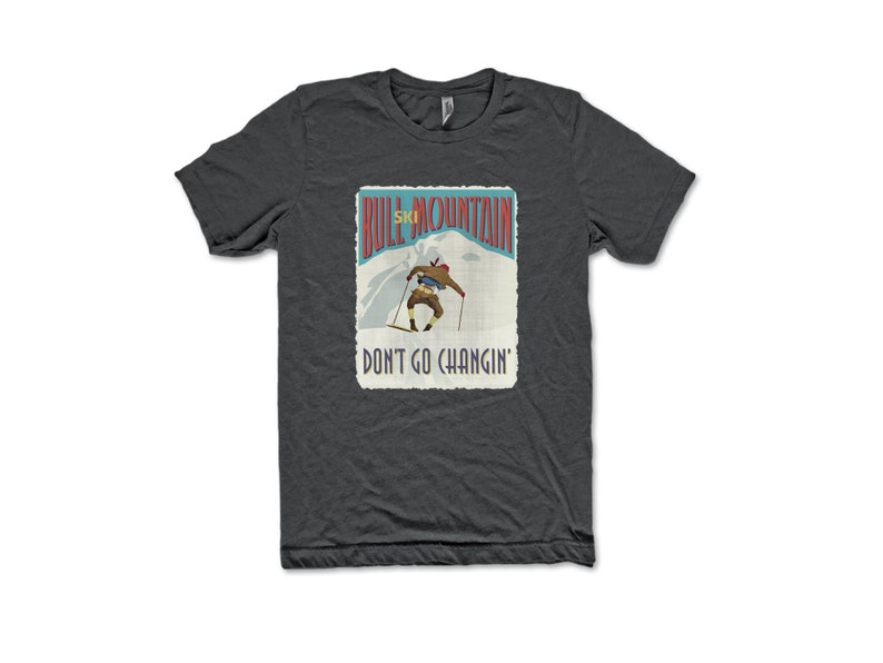 K&ouml;nnte beinhalten: Ein dunkelgraues T-Shirt mit einer Vintage-Illustration eines Skifahrers auf einem Berg. Der Text "Bull Mountain Ski" und "Don't Go Changin'" ist auf dem Shirt aufgedruckt.
