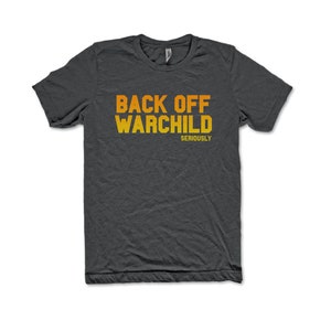 May include: A dark gray t-shirt with the text "BACK OFF WARCHILD" in orange and yellow lettering. The text "SERIOUSLY" is printed in smaller letters below the main text.