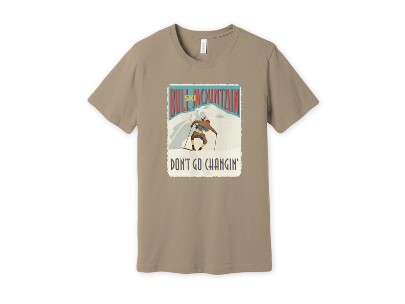 K&ouml;nnte beinhalten: Ein beiges T-Shirt mit einer Grafik im Vintage-Stil eines Skifahrers auf einem Berg. Die Grafik lautet "Bull Mountain Ski" und "Don't Go Changin'."