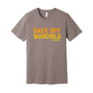 May include: A gray t-shirt with the text "Back Off Warchild Seriously" printed in orange and yellow.