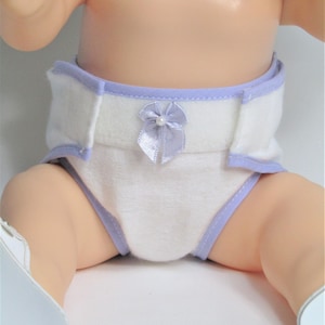 May include: A white diaper with a lavender trim and a lavender bow with a pearl in the center.