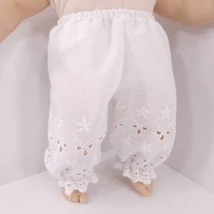 May include: White cotton doll pants with eyelet lace trim and floral embroidery.