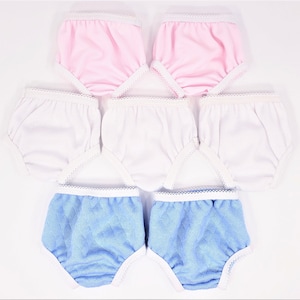 May include: A collection of baby underwear in various colors. The assortment includes pink, white, and blue pairs. Each pair features a white lace trim along the edges and waistbands. The blue pairs have a quilted texture.