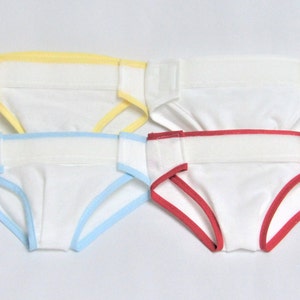 May include: Four white cloth diapers with colorful trim. The trim colors are yellow, blue, and red. Each diaper has a white waistband and leg openings with colored edging.