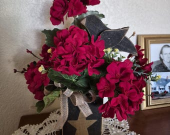 Arrangement for your primitive/country decor.  Table arrangement with artificial greenery, geraniums, wood crow & pip berries.