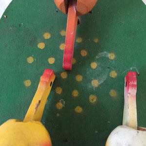 May include: A vintage wooden toy with three colorful birds. The birds are painted yellow, orange, and white with red accents. The birds are perched on a green circular base with yellow dots.