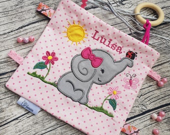 Puede incluir: Manta de confort para bebé rosa con un elefante gris, un sol, flores, una mariquita y una mariposa. La manta tiene un patrón de lunares rosas y el texto "Luisa" está bordado en ella.