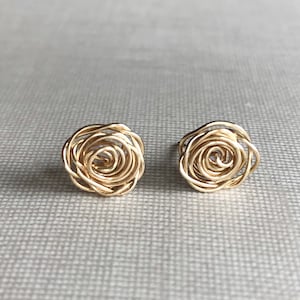May include: A pair of gold wire rose earrings. The earrings are made of thin gold wire that is twisted into a rose shape.