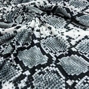 May include: White fabric with a black and grey snake skin pattern.