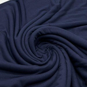 May include: A close-up of a navy blue fabric with a soft, smooth texture. The fabric is folded and draped, showing its drape and flow.
