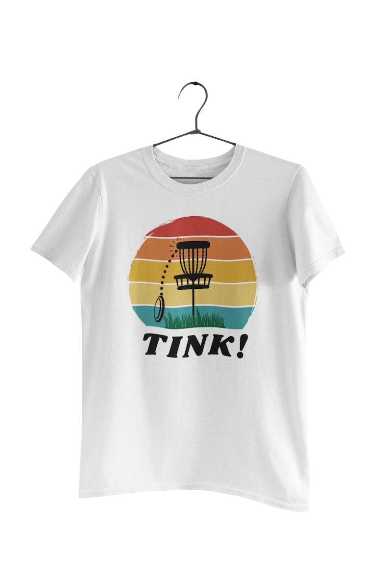 May include: White t-shirt with a retro sunset graphic featuring a disc golf basket and the text "TINK!"
