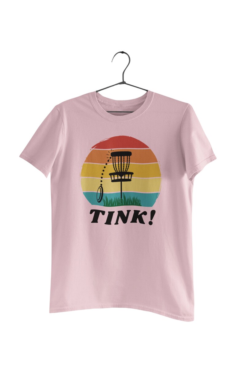 May include: Pink t-shirt with a retro sunset graphic featuring a disc golf basket and the text "TINK!"