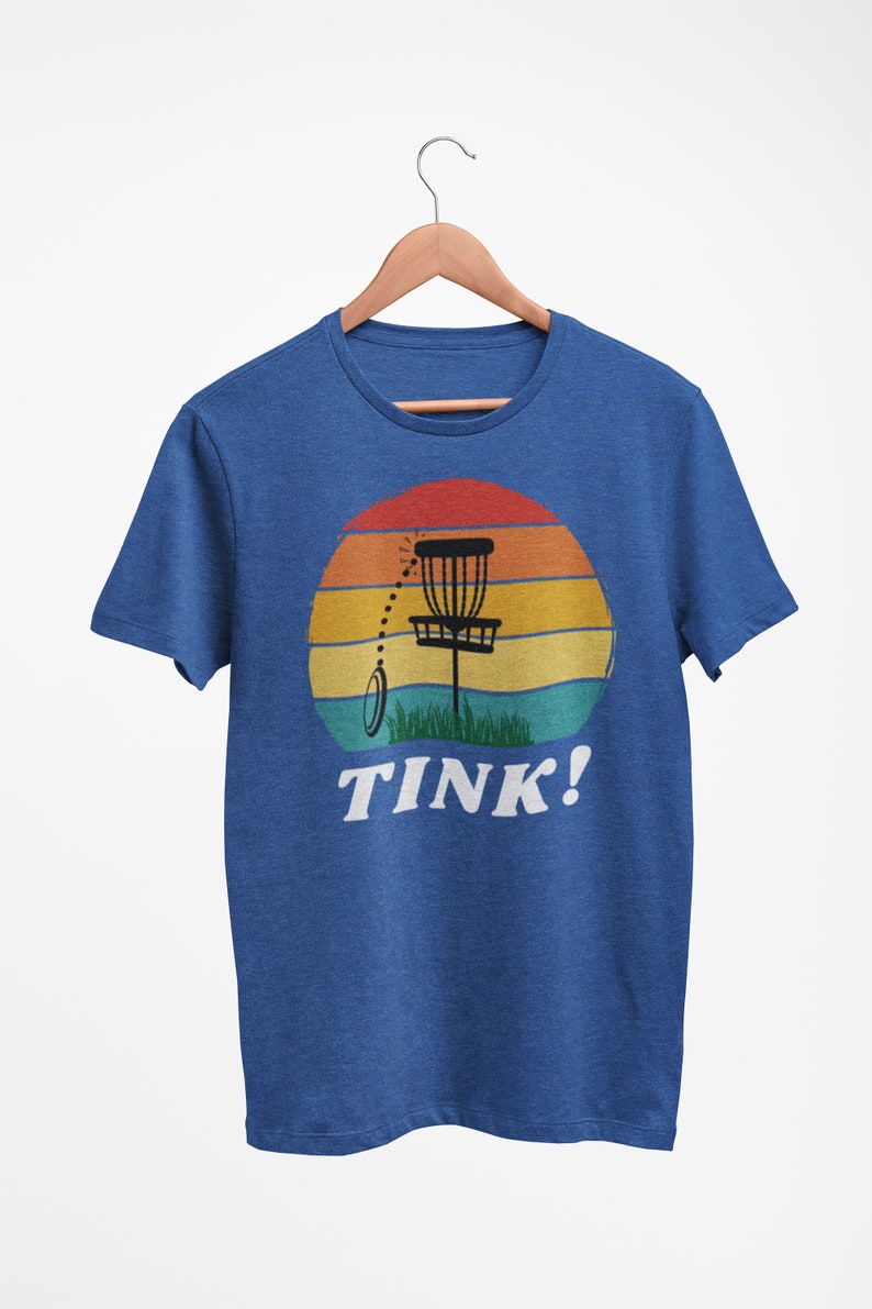 May include: A blue t-shirt with a retro sunset graphic featuring a disc golf basket and the text "TINK!"