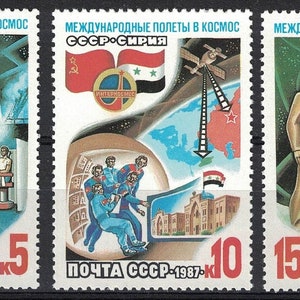 Può includere: Tre francobolli dell'URSS che raffigurano un programma spaziale congiunto con la Siria. I francobolli mostrano immagini di astronauti, un lancio di razzi, un satellite e un globo terrestre. Il testo sui francobolli recita "Voli internazionali nello spazio URSS-Siria" e "Posta dell'URSS 1987".