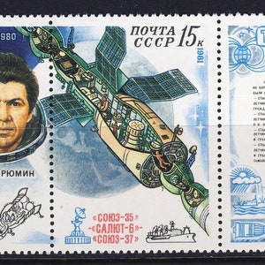 Puede incluir: Un sello postal soviético vintage que conmemora los 185 días que los cosmonautas Leonid Popov y Valeri Ryumin pasaron en el espacio. El sello presenta una ilustración colorida de la nave espacial Soyuz atracada en la estación espacial Salyut 6, junto con retratos de los cosmonautas. El texto en el sello dice "185 Sutok v Kosmose" (185 días en el espacio), "9-IV-11-X-1980", "Pochta SSSR 15k" y "1981".