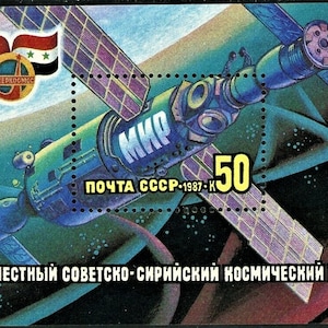 以下が含まれることがあります： ソビエト連邦の切手。青と緑の宇宙ステーションが描かれており、側面には「МИР」（平和）の文字が書かれている。切手には、「ПОЧТА СССР-1987-K」（ソ連郵便 - 1987 - K）と「50」という文字が黄色で書かれている。切手は、ソ連とシリアの共同宇宙ミッションを表している。