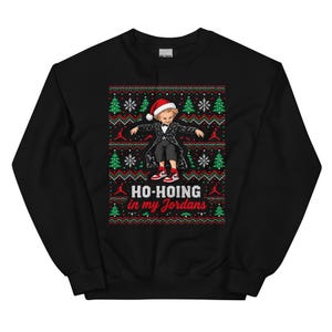 May include: A black crewneck sweatshirt featuring a graphic of a person in a tuxedo and Santa hat wearing red and white sneakers. The design includes green Christmas trees, white snowflakes, and the text HO-HOING in my Jordans.
