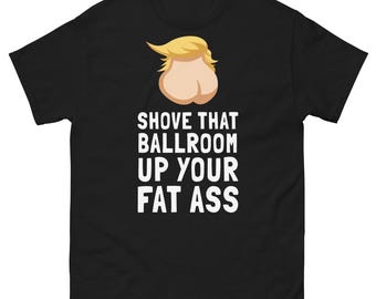 May include: A black short-sleeve t-shirt featuring a graphic of blonde hair atop a pair of buttocks. Below the graphic, white text reads: SHOVE THAT BALLROOM UP YOUR FAT ASS. The shirt has a crew neckline and a standard fit.