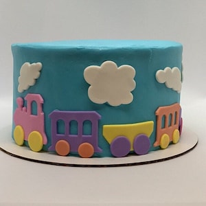 May include: A blue and white cake decorated with a train theme. The cake is decorated with fondant trains, clouds, and wheels. The trains are pink, purple, yellow, and orange.
