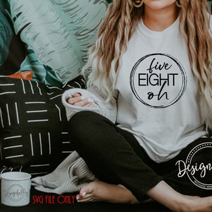 May include: A white t-shirt with the words "five EIGHT oh" in a black circle. The shirt is part of a design that includes the text "Designfully made" in a circle. The image also includes a mug and pillows.