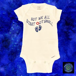 May include: A white baby onesie with blue text that reads "But we all start out small" with a red circle and two blue footprints with pink hearts.