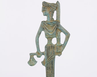May include: A green bronze statue of a blindfolded figure holding scales in one hand and a sword in the other. The figure is standing on a round base.