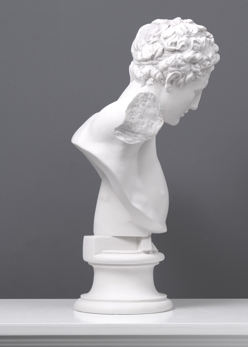May include: White plaster bust sculpture of a person with their head tilted down. The bust is on a white pedestal.