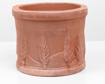 May include: Terracotta planter with a decorative design of wheat stalks around the rim.
