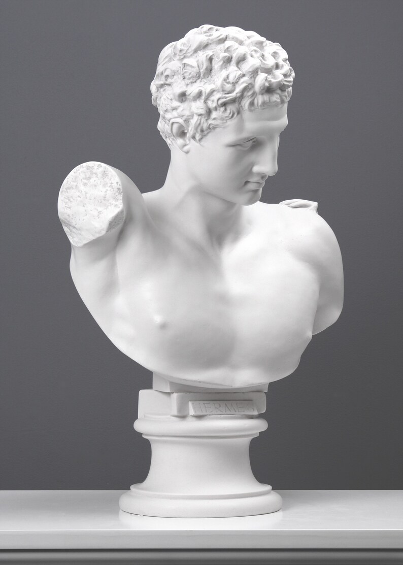 May include: White plaster bust sculpture of a man with short curly hair. The bust is on a white pedestal with the word "Hermes" inscribed on the front.