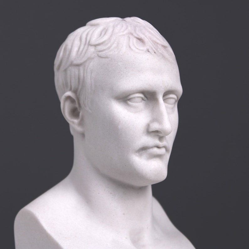 May include: A white marble bust sculpture of a man with short hair. The bust is a detailed representation of a person's head and shoulders.