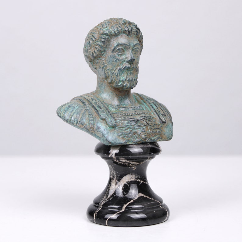 May include: A bronze bust of a man with a beard, on a black marble base. The bust is green and blue, and the man is wearing a toga.