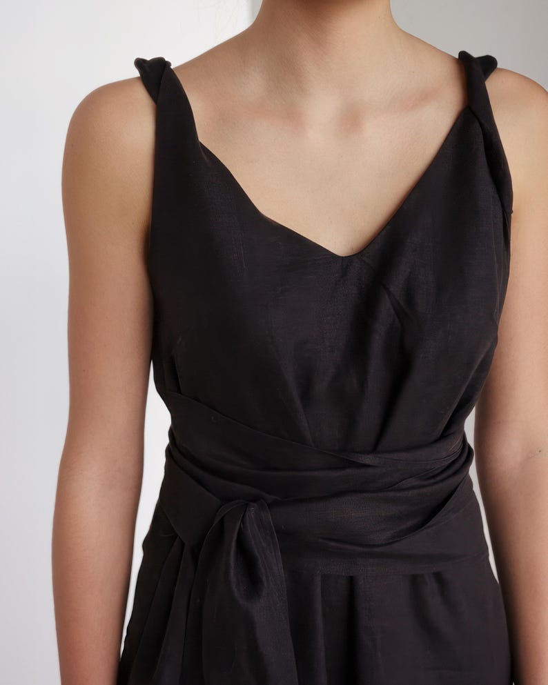 Ready to ship in 1 day, close-up of black linen midi dress with twisted shoulder straps, soft V-neckline, and wide wrap belt. Lightweight and breathable fabric, ideal for summer events, vacation evenings, or minimalist everyday wear.