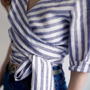 Close-up of the adjustable waist tie on the linen wrap blouse. Designed for flexible sizing and flattering fit, this organic summer top blends functionality with feminine style.