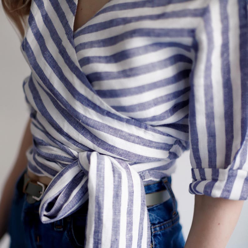Close-up of the adjustable waist tie on the linen wrap blouse. Designed for flexible sizing and flattering fit, this organic summer top blends functionality with feminine style.