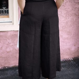 Ready to ship in 24 hours from USA — back view of black linen culottes with wide leg silhouette and elastic waistline for flexible fit. Lightweight and breathable, perfect for summer and plus size bodies. Designed for effortless everyday wear, travel, and modern minimalist style. Soft natural fabric, no back pockets for a clean, flattering look.