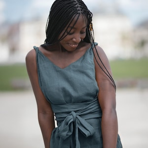 Ready to ship in 1 day, this soft green linen dress features twisted straps, a deep V-neckline, and a long belt that wraps at the waist for a flattering silhouette. Made from breathable organic linen, it's perfect for vacations, summer getaways, and relaxed city strolls. A feminine, timeless piece designed for women who love comfort and effortless style. Ideal as a thoughtful gift or a go-to summer outfit.