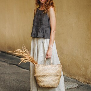 Natural linen wide leg culottes styled with a sleeveless dark top and straw bag. Relaxed fit, high waist with adjustable back, deep pockets, and flowy cropped silhouette. Perfect for plus size, beachy, boho or coastal grandma style. Breathable and comfy travel pants for summer, lounging, or vacation. Ready to ship in 24 hours from USA with fast delivery across the US.