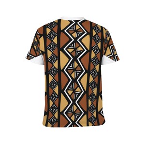Puede incluir: Una camiseta blanca con un patr&oacute;n geom&eacute;trico marr&oacute;n, negro y blanco. El patr&oacute;n est&aacute; inspirado en el arte tribal africano.