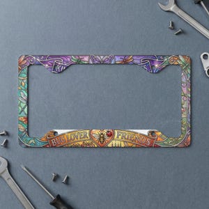 May include: A rectangular license plate frame featuring a colorful stained glass style design with dragonflies, butterflies, and floral patterns. The bottom section displays a banner with the text BUG LOVER FRIENDS and a central bee and ladybug.
