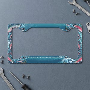 May include: A rectangular license plate frame featuring a vibrant blue water pattern with stylized salmon swimming throughout. The design includes swirling currents, bubbles, and aquatic elements integrated into the frame's border.