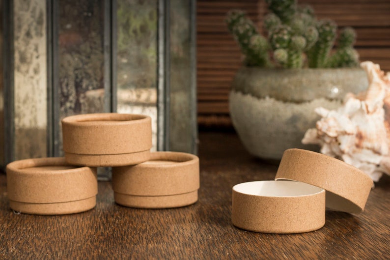 May include: Four brown cardboard containers with lids, three are closed and one is open, sitting on a wooden surface.