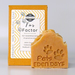 May include: A bar of orange-coloured pet shampoo soap with the text "Pets Eden Days" and paw prints. The soap is packaged in a yellow box with the text "Fur Factor" and "Eden Days".