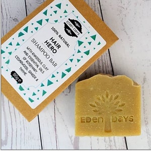 May include: A 90g bar of natural hair shampoo with rhassoul clay and essential oils of rosemary, cedarwood, ginger, and thyme. The bar is packaged in a brown box with a white label that says "Hair Hero Shampoo Bar" and "Eden Days".