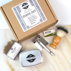 May include: A zero waste shave set in a brown box. The set includes shave soap, a shave brush, a safety razor, a soap tin, and blades. The box has a label that reads "Eden Days" and "Shave Set".