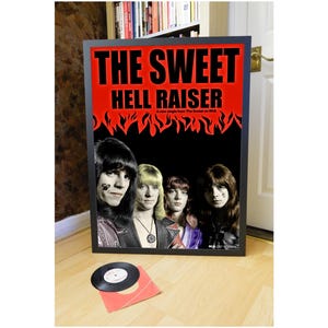May include: A framed poster with a red background and black flames. The text "THE SWEET HELL RAISER" is in black letters. The poster features a black and white photo of a band with four members. The text "A new single from The Sweet on RCA" is in white letters.