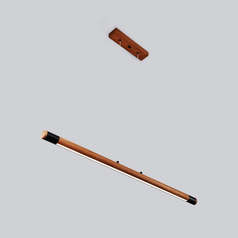 May include: A long, wooden pendant light with black end caps. The light is suspended from a wooden ceiling mount.
