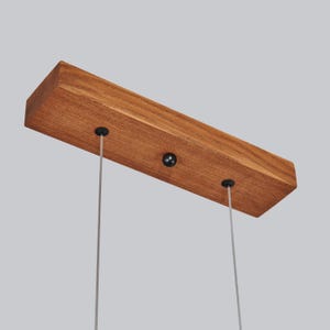 May include: A wooden ceiling mount with three black metal hooks for hanging a light fixture.