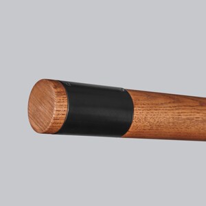 May include: Close-up of a wooden and black metal rod. The rod is made of natural wood with a dark brown finish. The metal portion is black and has a smooth, polished finish.